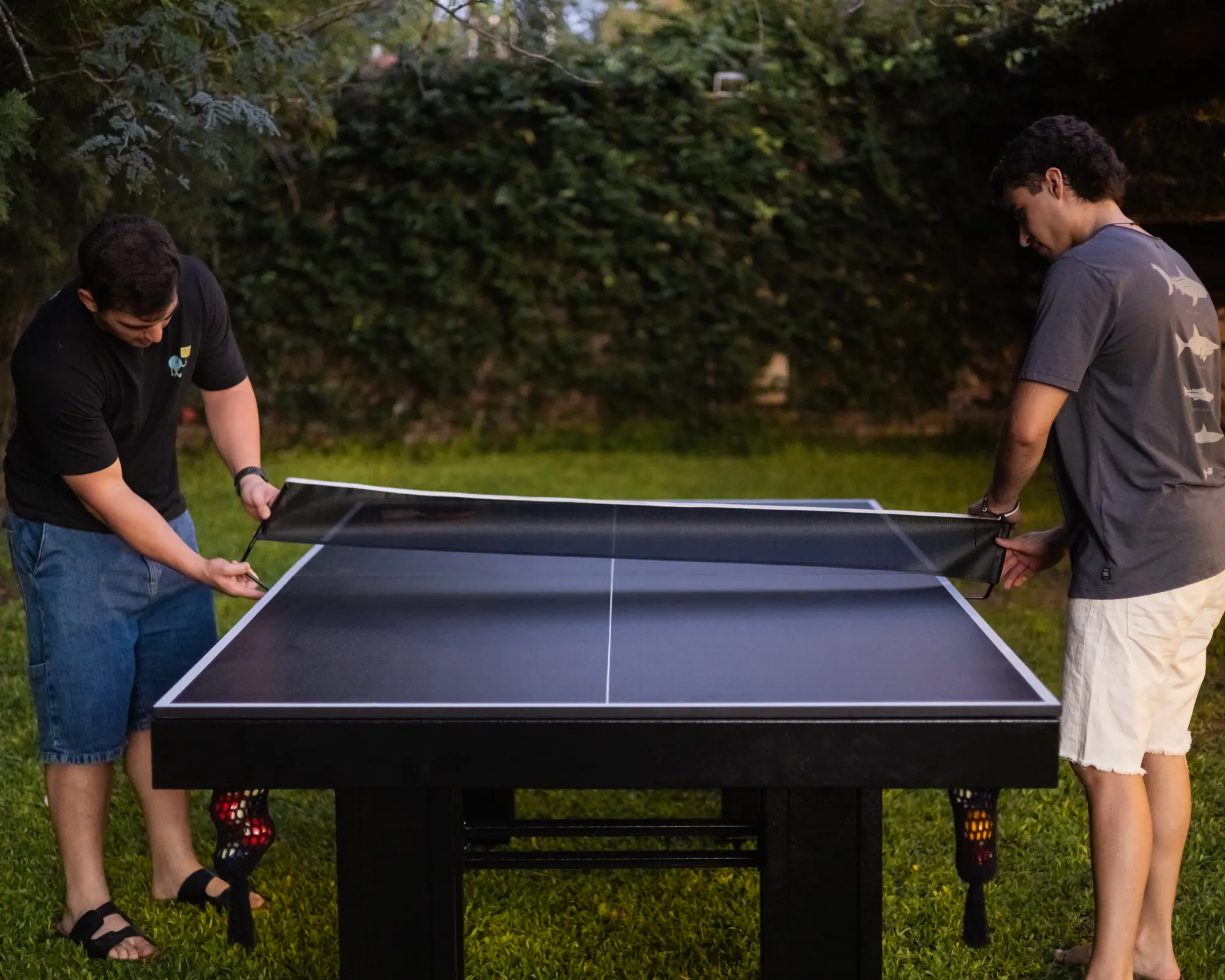 Tres amigos colocando la red sobre la tapa de ping pong de la BlackSteel®
