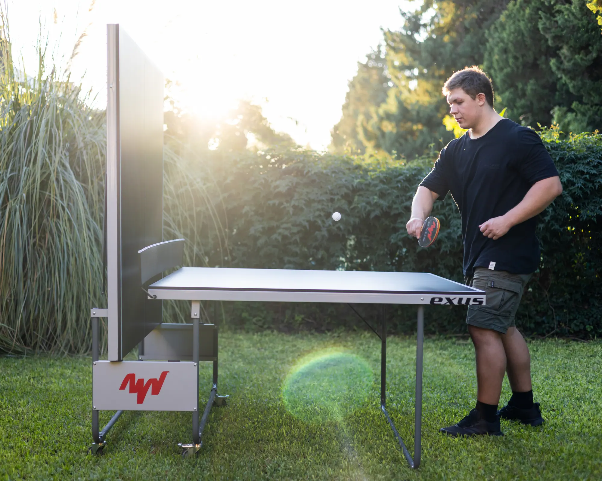 Mesa de ping pong Gladiator abierta en un jardín, con un jugador sacando